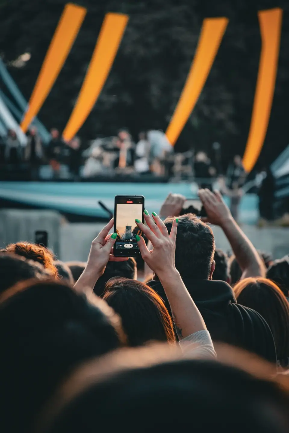 A guest photographing the stage at an outdoor live event