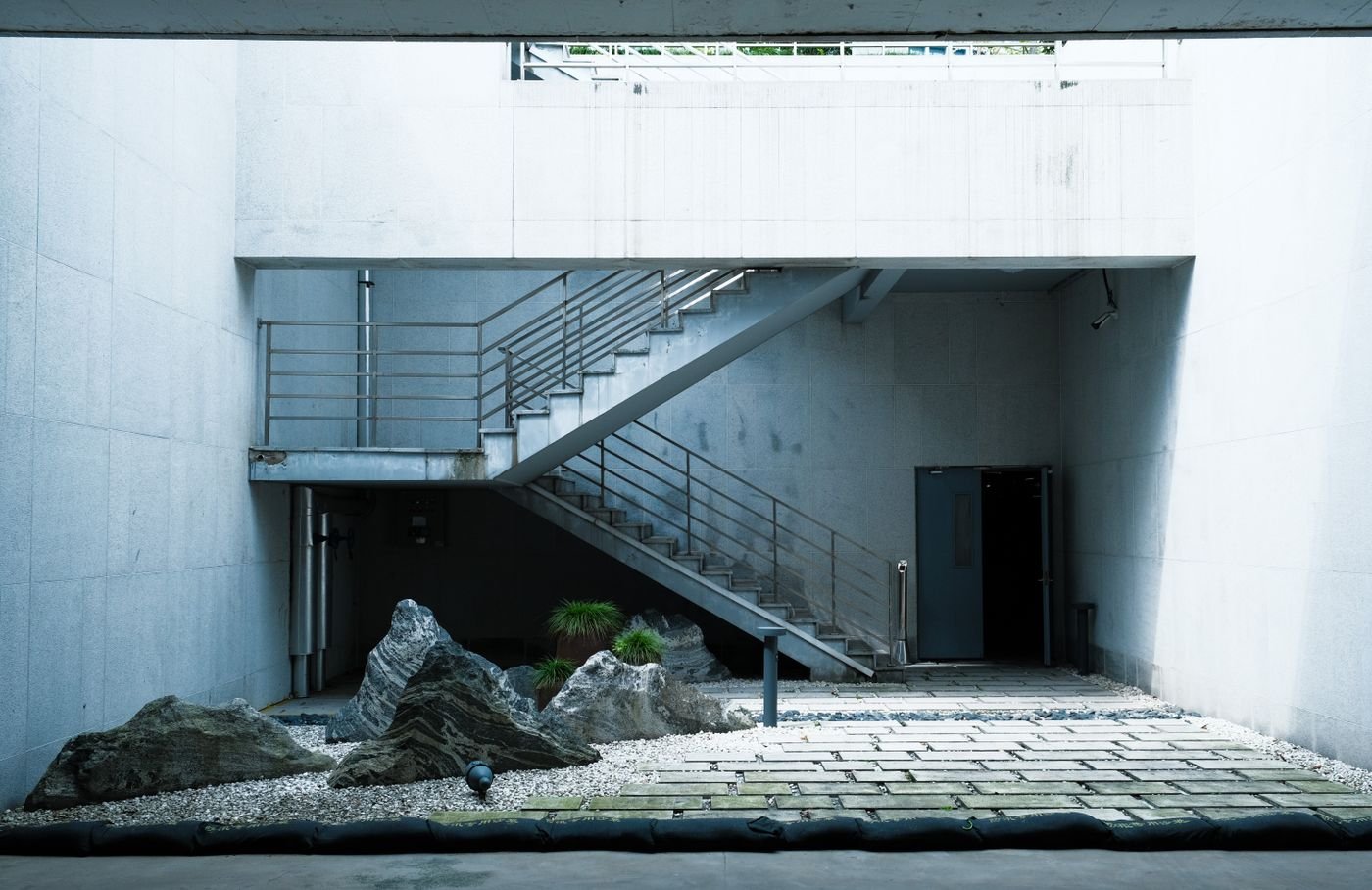 A quiet architectural courtyard with stone gardens and connecting stairways